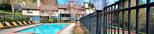 A pool and tennis court are surrounded by a black fence.