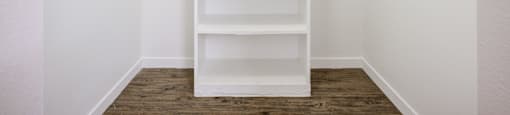Apartments For Rent In Glendale, AZ - Spectra West - Spacious Closet With Wood-Look Flooring, Hanging Racks, And Shelf Stand.