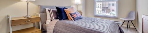San Rafael, CA, Apartments Near Mount Tamalpais State Park - Rafael Town Center - Spacious Bedroom With Plush Carpeting, BEd, Nightstands with Lamps, Dresser, Chair, And Large Picture Window With Blinds.
