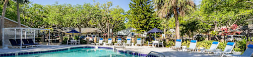 a pool with lounge chairs and trees in the background