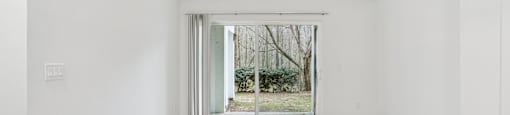 A room with a ceiling fan and sliding glass doors leading to a garden.