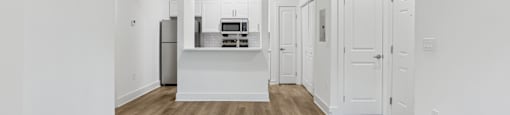 A kitchen with white cabinets and a wooden floor.