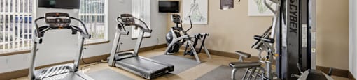 A spacious gym with treadmills, elliptical machines, and a weight machine.