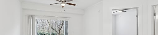 A room with a ceiling fan and sliding glass doors.