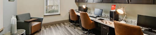 A room with brown chairs and a desk with a computer.