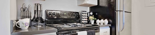 One-Bedroom Apartments in Daly City, CA - Serra Commons - Kitchen with Stainless-Steel Appliances, White Cabinets, and Tiled Floor.