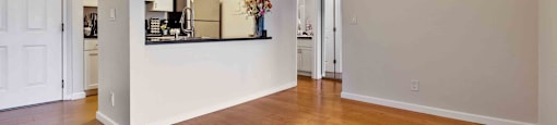 Dog-Friendly Apartments in Daly City, CA - Serra Commons - Living Room with Wood-Inspired Flooring, Ceiling Fan, and View of Kitchen.
