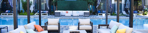A poolside seating area with a variety of cushions and chairs.