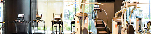 A gym with a variety of exercise equipment including treadmills, stationary bikes, and weight machines.
