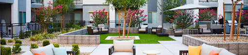 A patio with a couch, chairs, and a table in front of a building.