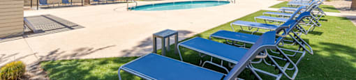 Resort-style pool seating area at Sono Tempe Apartments in Tempe, AZ with shaded loungers and outdoor relaxation space.