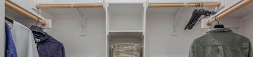 a walk in closet with a white shelving unit and wooden rails