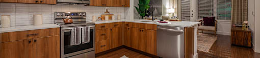 2-Bedroom Apartments in Old East Dallas, TX - 4600 Ross - Kitchen with Hardwood-Style Flooring, Wood Cabinets, White Countertops, White Tile Backsplash, and Stainless Steel Appliances