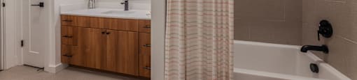 One-Bedroom Apartments in Old East Dallas, TX - 4600 Ross - Bathroom with Wood Cabinets, White Counters, a Shower with a Tub, and Tile Flooring