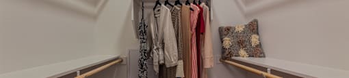 a walk in closet with white walls and wooden shelves