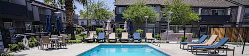 A swimming pool with a diving board and lounge chairs.
