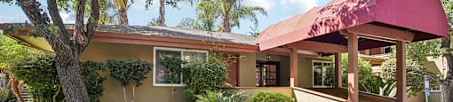 a house with a red awning and a tree in front of it