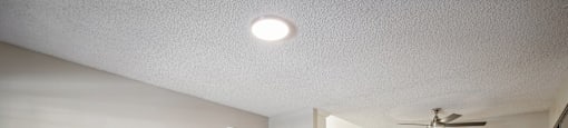 an empty living room and kitchen with a ceiling fan