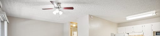an empty living room and kitchen with a ceiling fan