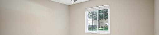 an empty living room with a ceiling fan and a window