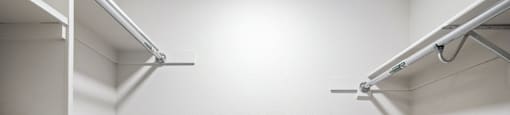 an empty walk in closet with white walls and white hangers