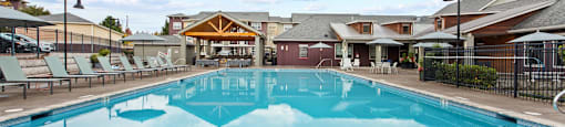 Apartments in Tigard, OR, with In-Unit Washer and Dryer - Sygnii - Swimming Pool with Lounge Seats, Umbrella Tables with Chairs, and Shaded Patio.
