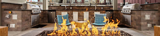 A patio with a fire pit and chairs.