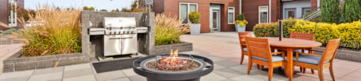 A patio with a fire pit and chairs.