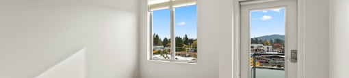 A room with a wooden floor and a window overlooking a cityscape.