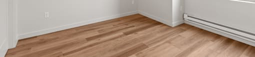 A room with wooden flooring and a window showing a balcony outside.
