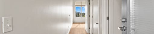 A long hallway with white walls and wood floors.