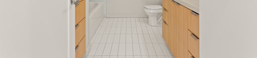 A white tiled bathroom with a toilet, sink, and shower.