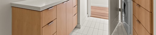 A bathroom with a sink, mirror, and a washer and dryer in the doorway.