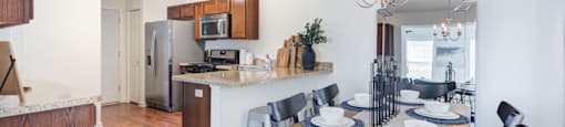 a dining area with a wooden table and chairs and a kitchen in the background