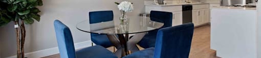 A dining room with a glass table and blue chairs.