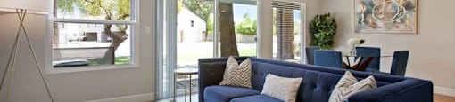 A living room with a blue couch and a white coffee table.