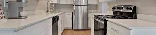 A kitchen with white cabinets and a stainless steel refrigerator.