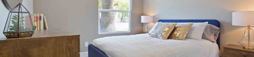 A bedroom with a bed, nightstand, and a mirror on the wall.
