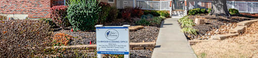 a sidewalk in front of a house with a sign on it
