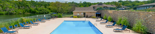 a swimming pool with blue chairs around it next to a river