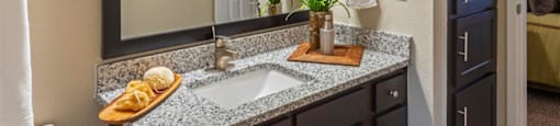 1 BR Apartments in League City TX - Anchor at South Shore - Bathroom with Wooden Cabinets on the Vanity, Granite Countertops, and a Mounted Mirror