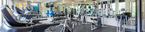 a gym with weights and cardio equipment in a building with windows