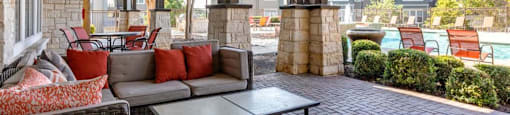 Two Bedroom Apartments in San Antonio TX - Club at Stone Oak - Outdoor Lounge by the Pool Area with Cuchsioned Seating, Couches, Tables, and Chairs, with a Coffee Table
