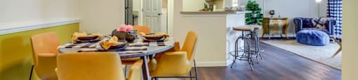 Apartments for Rent in San Antonio TX - Club at Stone Oak - Dining Room with Wood-Style Flooring, Hanging Light, and Yellow Accent Wall