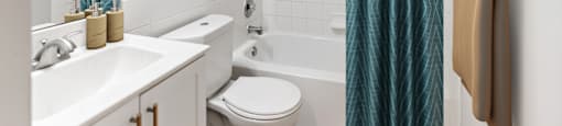 A bathroom with a white sink, toilet, and bathtub with a blue shower curtain.