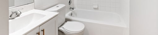 A white bathroom with a toilet, sink, and bathtub.