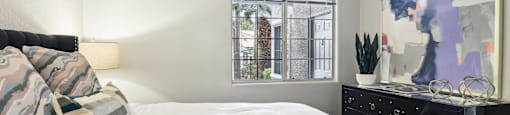 A bedroom with a bed, dresser, and a painting on the wall.