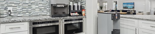 A modern kitchen with a stone wall and stainless steel appliances.