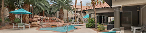 A pool surrounded by palm trees and a patio area.