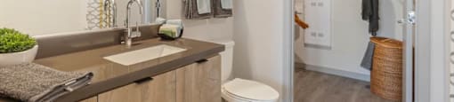 A bathroom with a toilet, sink, and a mirror.